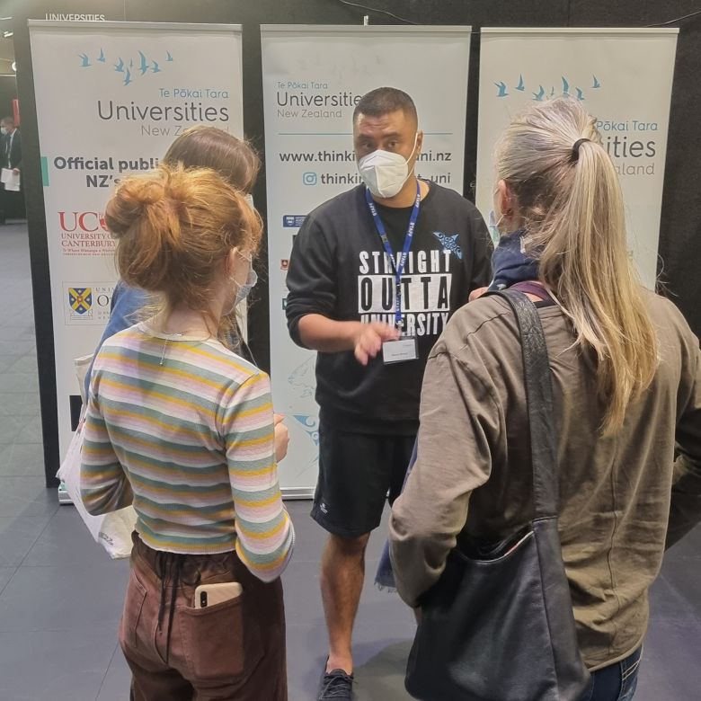 Xavier Breed helping three students at one of this year's school-leaver careers expos against a backdrop of information banners