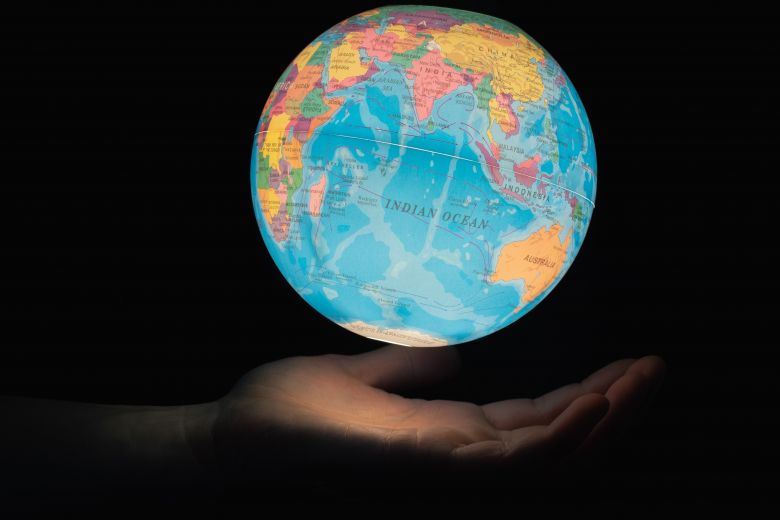 A lit world globe falls into a hand. Image: Greg Rosenke/Unsplash